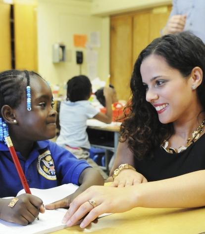 Teaching UFT teacher with curly brown hair gazing at African-American student