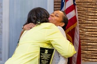 Two women share a hug after one of them receives an award. 